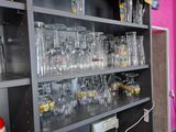 bottles and glasses on a shelf in a room with pink walls