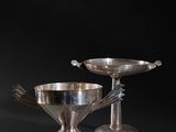 a pair of silverplated bowls and spoons on a black background