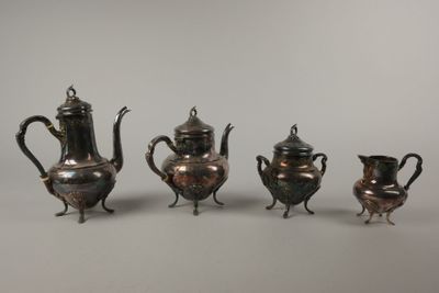 trois théières en argent et une cafetière sur une table