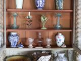 many vases and bowls on a shelf in a cabinet