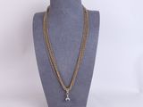 a gold chain necklace with a star charm hangs on a mannequin