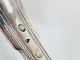 an antique silver plate with a handle on a white surface