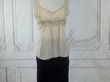 beige and black dress on a mannequin stand in front of a white wall