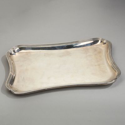 une assiette en argent aux bords incurvés sur un fond gris