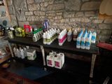 many bottles of liquid on a shelf next to a brick wall