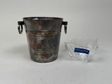 a metal bucket and a glass on a table