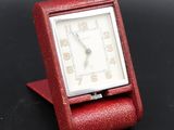 an image of a small red watch sitting on top of a black table