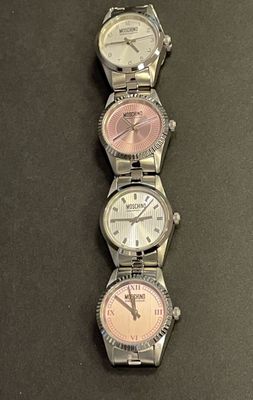 four different watches are lined up on a black surface