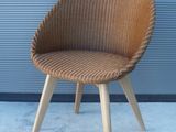 une chaise en osier avec des pieds en bois et une assise marron