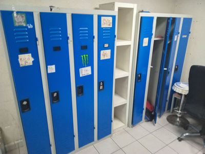 several blue lockers are lined up in a room with a computer chair