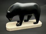 sculpture représentant un ours noir posée sur un socle en marbre, sur fond noir