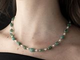 woman wearing a black top and a green necklace with silver beads
