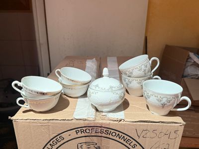 six cups and a saucer in a box on a table