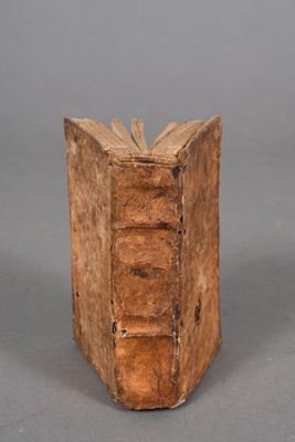 an old wooden book is sitting on a gray surface
