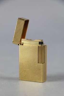 un gros plan d'un briquet doré posé sur une surface blanche