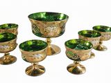 un ensemble de verres à pied et de tasses en verre vert posés sur une table