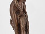 l'image d'une statue de bronze représentant une femme assise sur un rocher