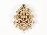 a gold brooch with a cross on it on a white surface