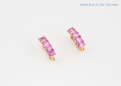 une paire de boucles d'oreilles en saphir rose posées sur une surface blanche