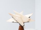sculpture représentant une étoile blanche posée sur un socle en bois, sur une surface blanche