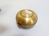 une petite boîte dorée posée sur une table blanche