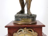 a statue of a man holding a clock on top of a table