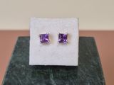 une paire de boucles d'oreilles en amethorate posées sur un bloc de marbre