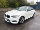 La BMW M140i blanche est garée sur un parking.