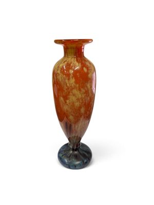 un vase posé sur un support sur une surface blanche