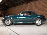 a green sports car in a garage with a brick wall