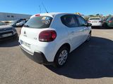 the back of a white car is parked in a parking lot