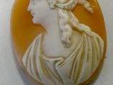 carved cameo of a woman in a white dress on a white surface
