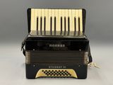 a close up of a black accordion on a white surface