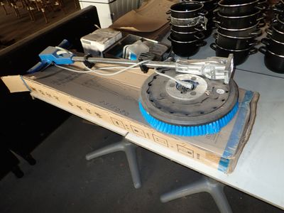 une table sur laquelle sont posés des casseroles et des poêles, ainsi qu'une brosse