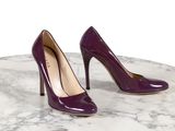 des talons hauts violets posés sur une table en marbre, sur fond blanc