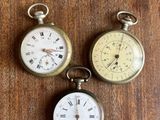 trois types différents de montres de poche posées sur un support en bois
