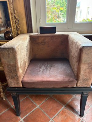 fauteuil en velours marron placé devant une fenêtre, dans une pièce au sol en briques rouges