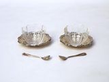 pair of silver plated cups and saucers with spoons on a white surface