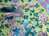 a yellow plate with a peacock and flowers on it