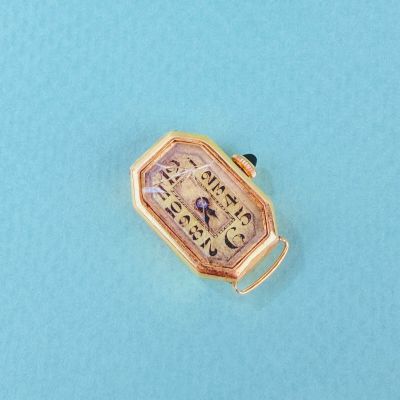 une petite montre posée sur une surface bleue