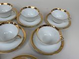 six cups and saucers with gold rims on a white table