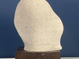 marble sculpture of a head on a wooden base against a blue wall