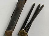 pair of antique brass scissors and a leather case on a white surface
