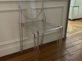 a clear plastic chair sitting in front of a white wall