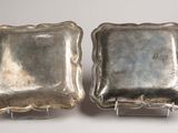 pair of silver plated dishes on stands on a white surface