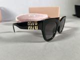 black sunglasses with gold letters and a pink case on a table