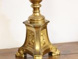 a gold lamp on a wooden table with a white wall in the background