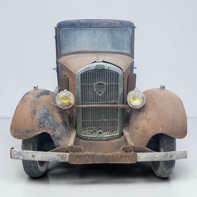 une vieille voiture toute rouillée, abandonnée par terre