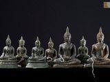 cinq statues de bouddhas assis en rang sur une table