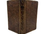 an old book with a brown cover and gold trim on a white background